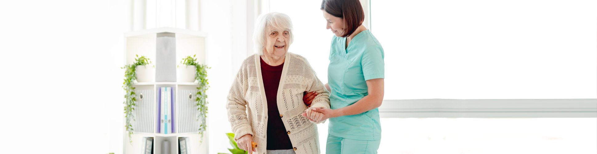 woman caregiver helping a senior to walk