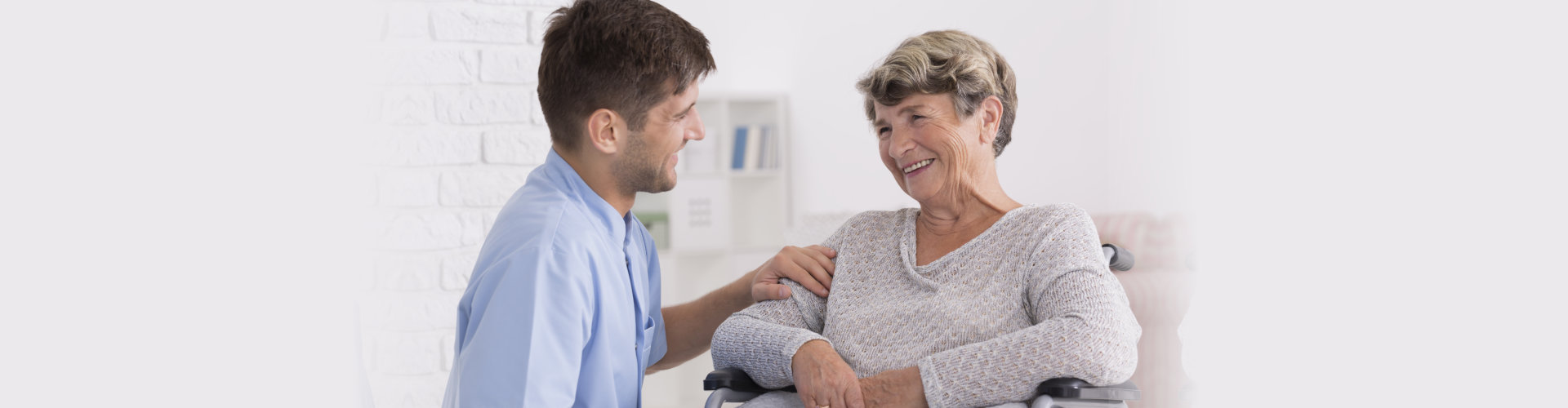 cargiver man and a senior woman smiling at each other