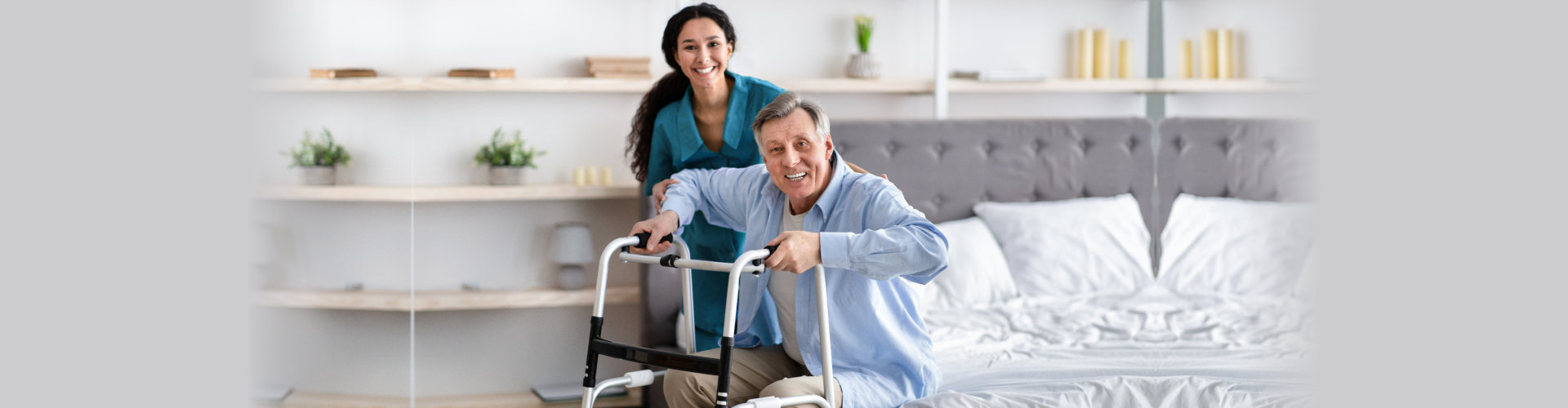 caregiver assisting a senior man on a walking frame to stand up